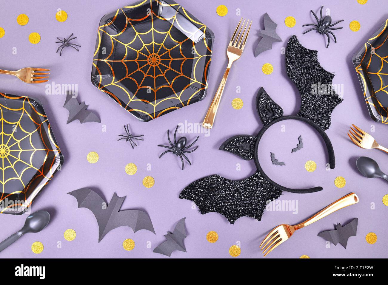 Halloween fiesta plana con placas de tela de araña, diadema de murciélago traje, arañas y confeti sobre fondo violeta Foto de stock