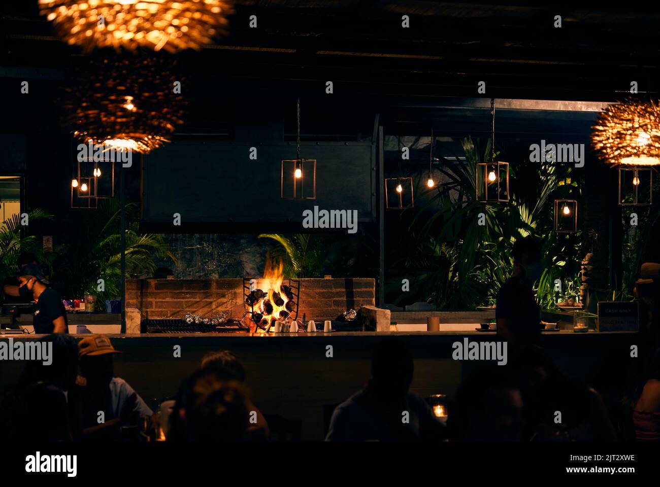 Un restaurante en Tulum, México durante la noche con lámparas decorativas  naranjas y un fuego iluminando el interior Fotografía de stock - Alamy