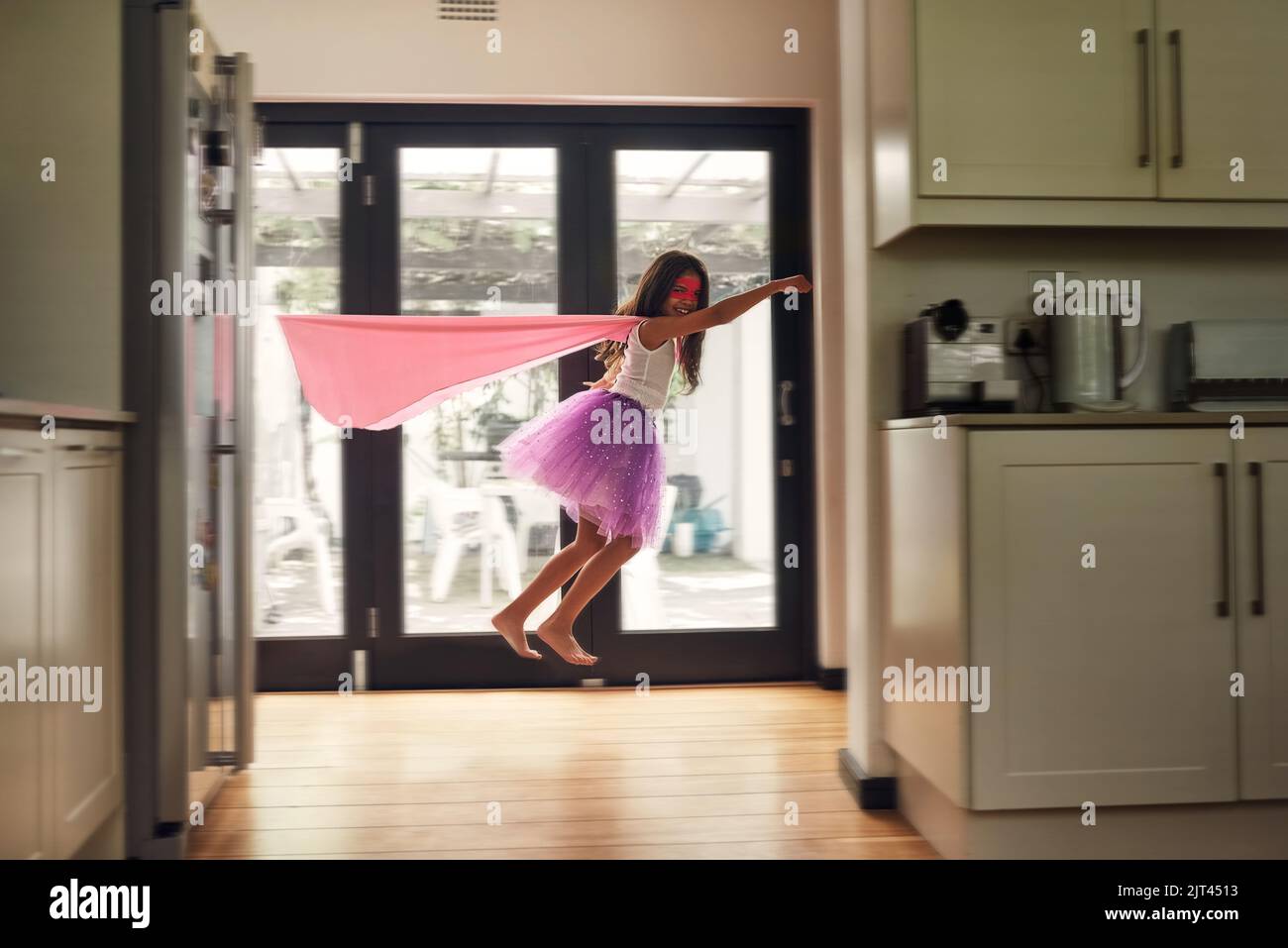 Hora del despegue. Retrato de una niña fingiendo volar como superhéroe. Foto de stock