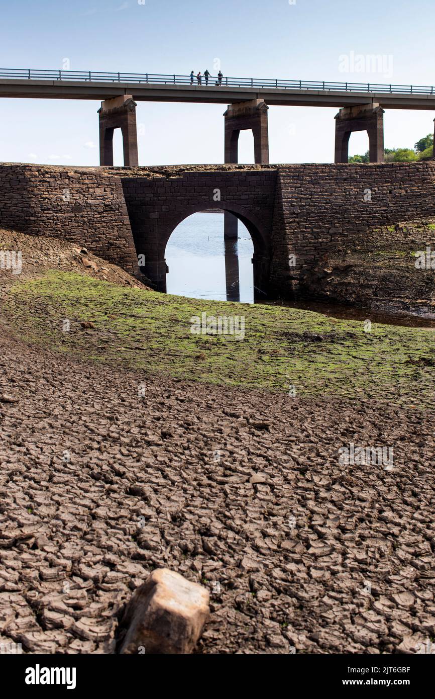 Ripponden,West Yorkshire, Reino Unido, 28th de agosto de 2022 Tiempo en el Reino Unido Baitings Dam se encuentra en su nivel más bajo en la memoria reciente. El embalse de Yorkshire Water, cerca de Ripponden, es tan seco que el antiguo puente de los caballos de vapor ha sido expuesto - sumergido desde que el embalse fue inundado en la década de 1950s - y el lecho de lo que una vez fue un lago ahora se asemeja a un paisaje desértico. Baitings se ha convertido en una atracción turística en las últimas semanas, ya que los niveles nacionales de agua en los embalses han caído a su nivel más bajo desde 1995. Crédito: Windmill Images/Alamy Live News Foto de stock