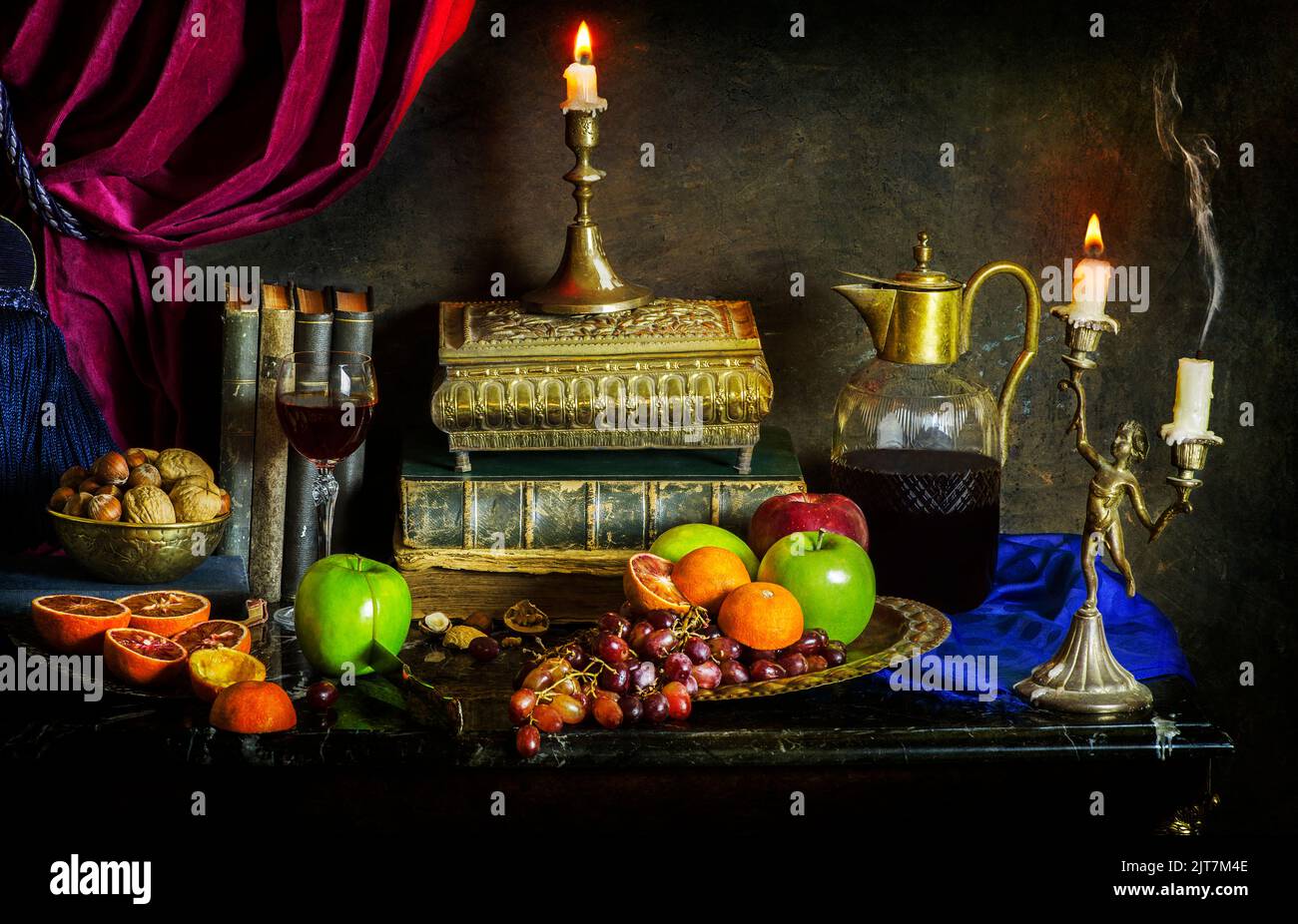Bodegón clásico con frutas frescas con libros de época, deliciosa bebida, frutos secos, velas iluminadas y vieja caja de cobre sobre fondo vintage. Foto de stock