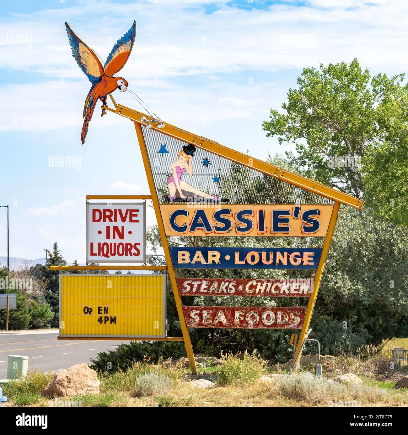 El histórico y moderno letrero de neón al borde de la carretera de mediados de siglo para el bar y salón Cassie en Cody, Wyoming. El signo para el club de la cena ofrece filetes, pollo, Foto de stock