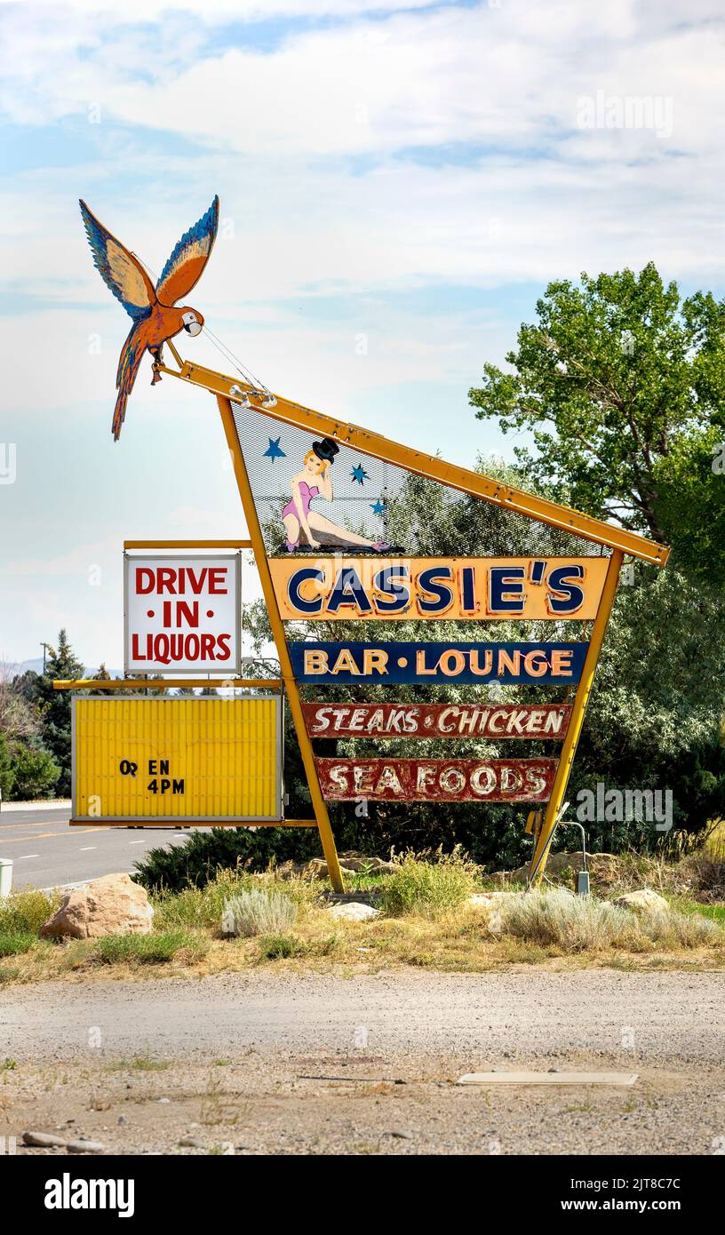El histórico y moderno letrero de neón al borde de la carretera de mediados de siglo para el bar y salón Cassie en Cody, Wyoming. El signo para el club de la cena ofrece filetes, pollo, Foto de stock