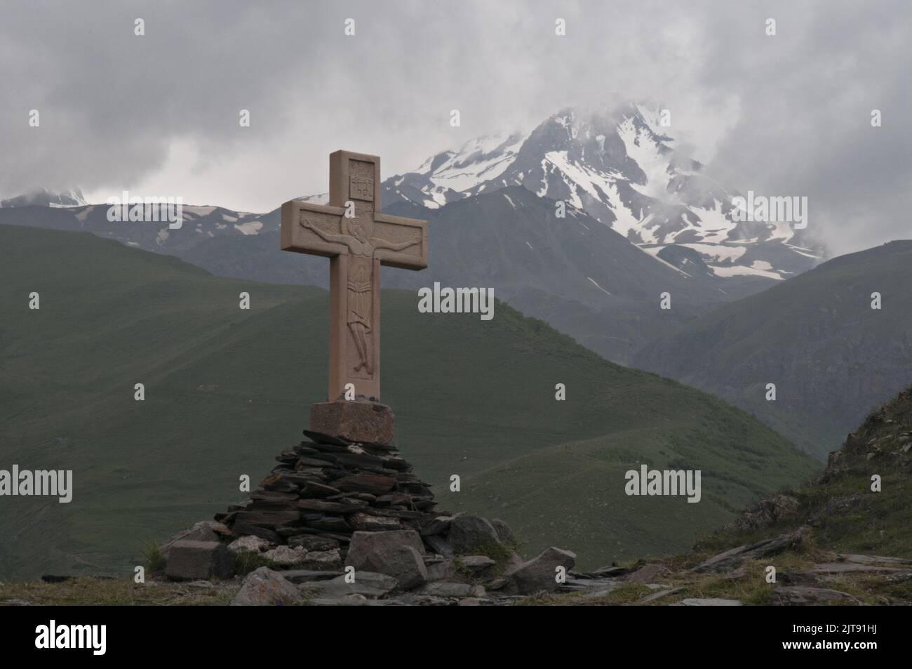 Cruz azotada por el viento cerca de la iglesia Tsminda Sameba (o Gergeti), con vistas al monte Kazbek en el Alto Cáucaso de la república de Georgia Foto de stock