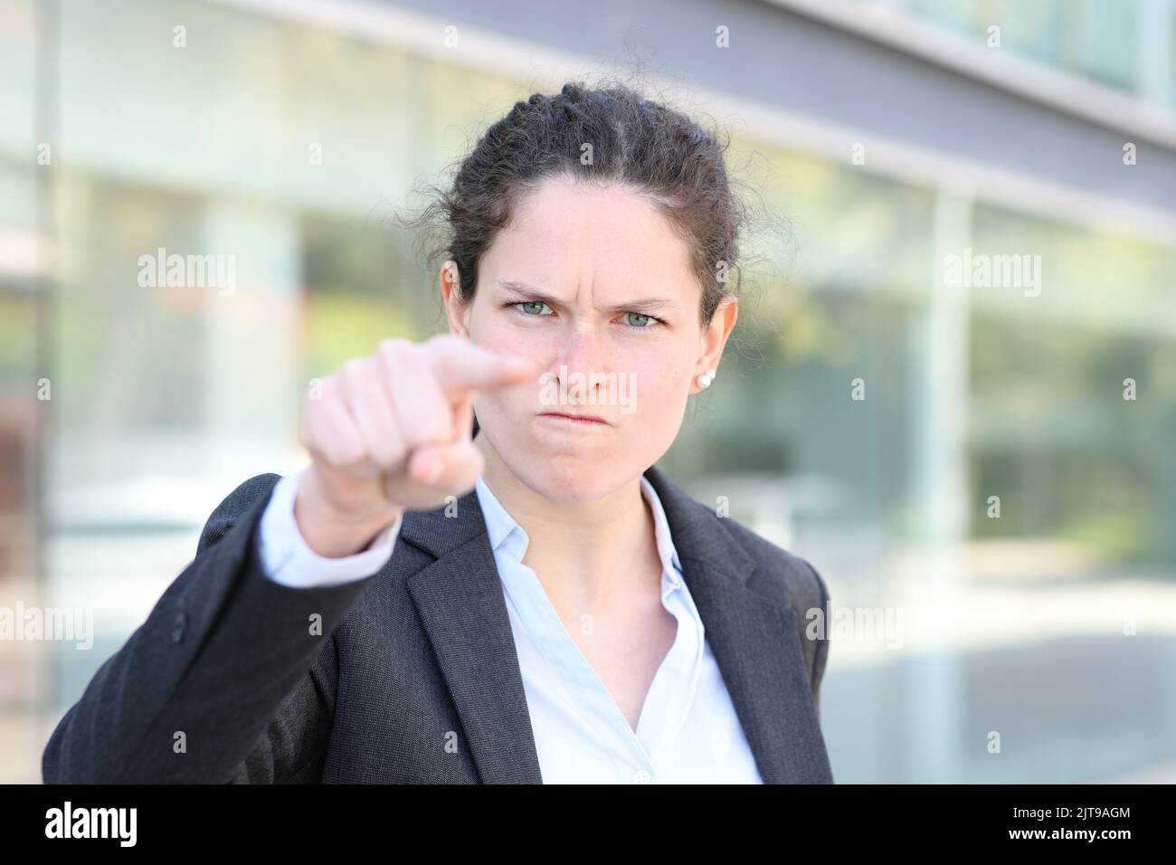 Vista frontal retrato de una mujer de negocios enojada acusando que le señala en la calle Foto de stock