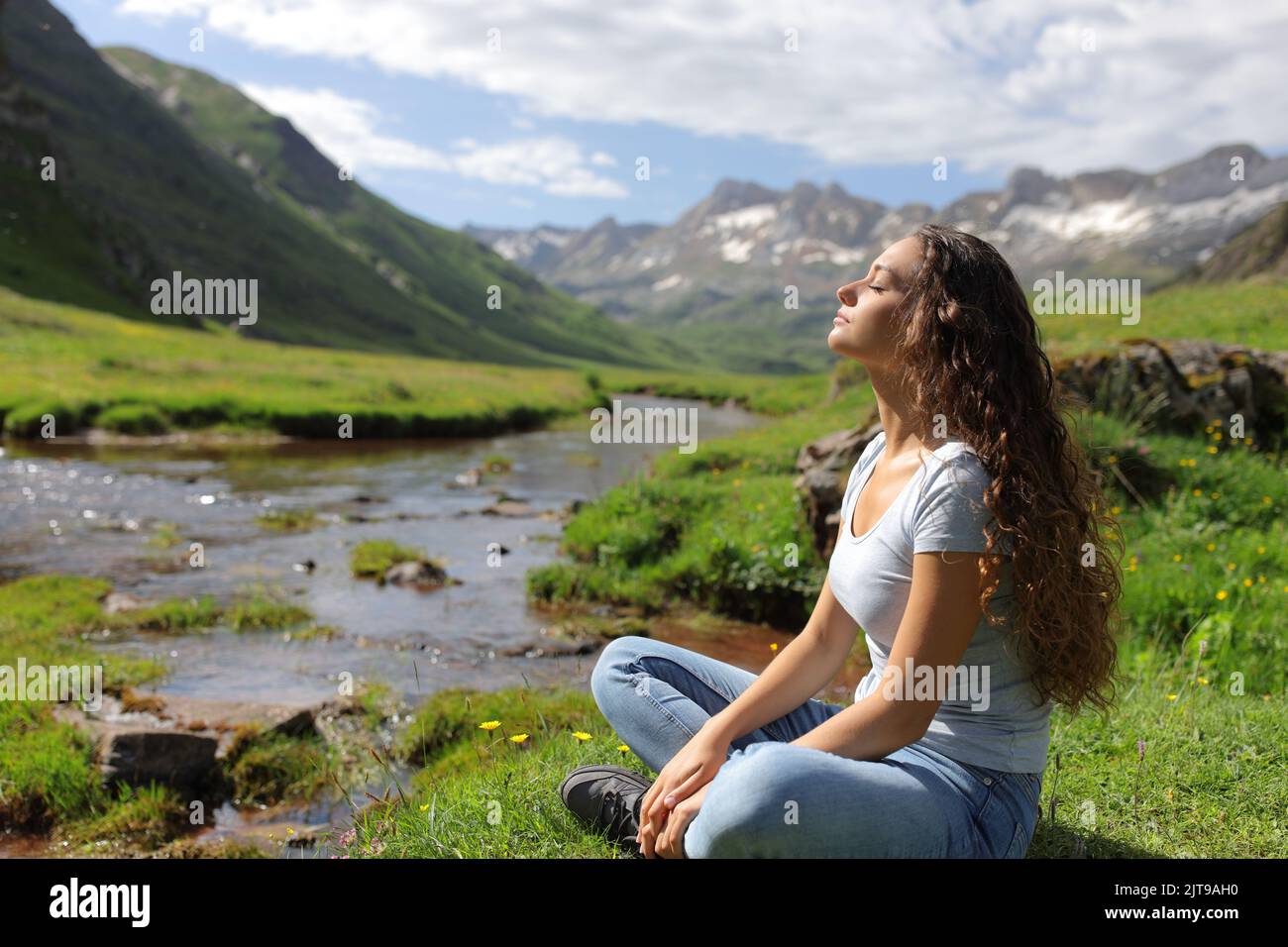 Vista lateral retrato de una mujer casual descansando respirando en un valle de montaña Foto de stock
