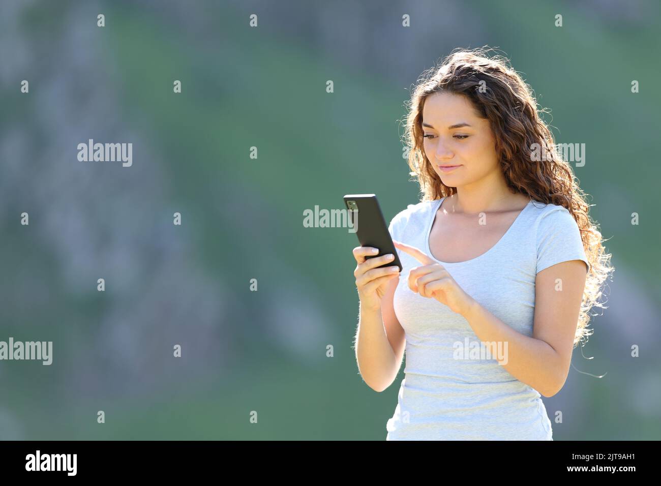 Mujer informal con un teléfono inteligente en la montaña Foto de stock