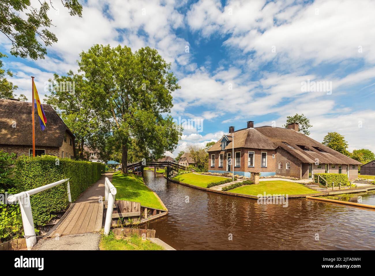 Antiguas casas rurales y un pequeño puente en el antiguo pueblo holandés de Giethoorn Foto de stock