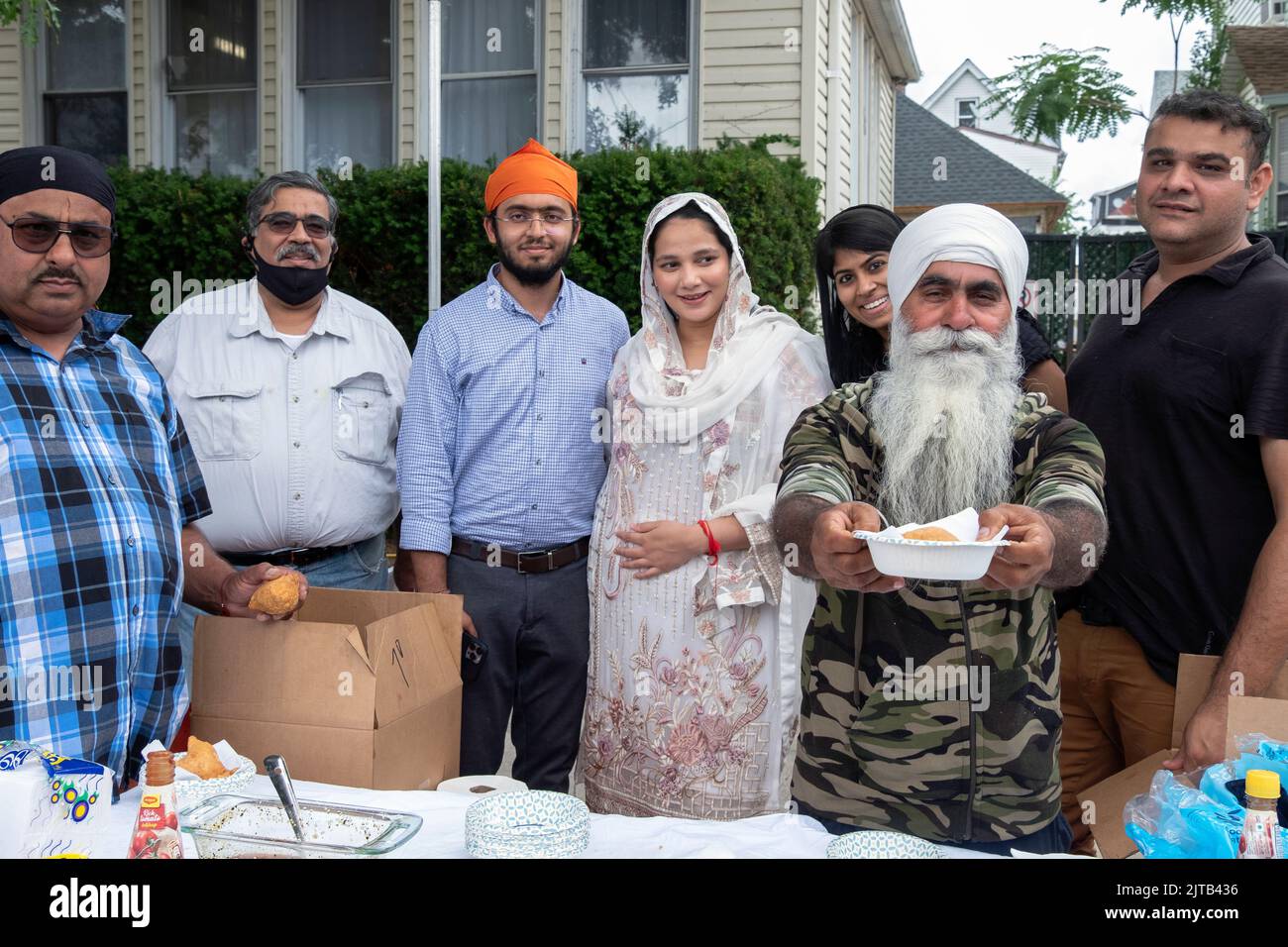 Voluntarios en el desfile de Nagar Kirtan Sikh reparten somosa vegetariana, una pastelería vegtaria. En Richmond Hill, Queens, Nueva York. Foto de stock