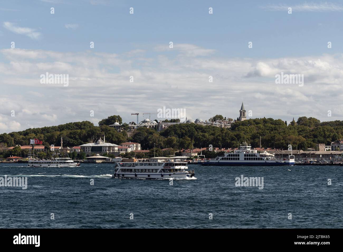 Vista de los barcos turísticos del Bósforo que pasan delante del Palacio Topkapi en Estambul. Es un soleado día de verano. Foto de stock