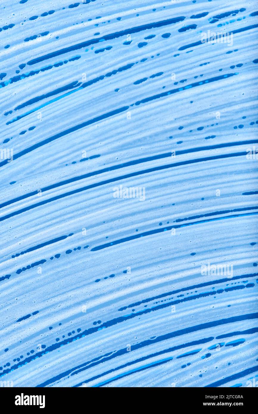 Vista superior de una superficie de vidrio azul cubierta con espuma de jabón. Fondo monocromático sin personas, concepto de limpieza. Foto de stock