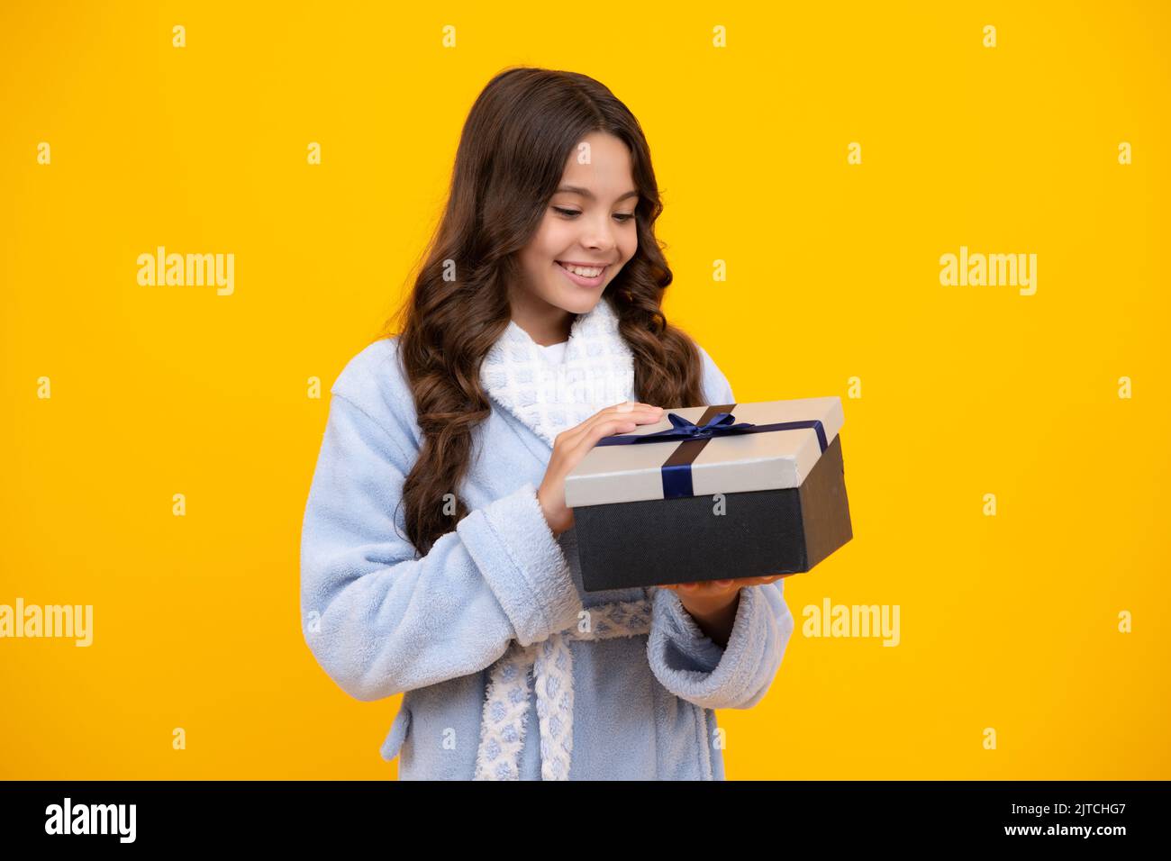 Niño adolescente sosteniendo la caja de regalo sobre fondo aislado amarillo. Regalo para cumpleaños infantil. Caja de regalos de Navidad o Año Nuevo. Día de San Valentín. Foto de stock