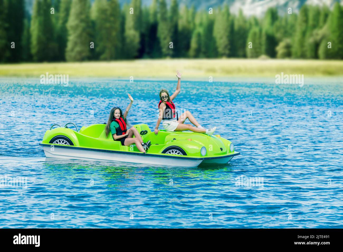 Niñas en un barco verde a pedales en un lago de montaña Foto de stock