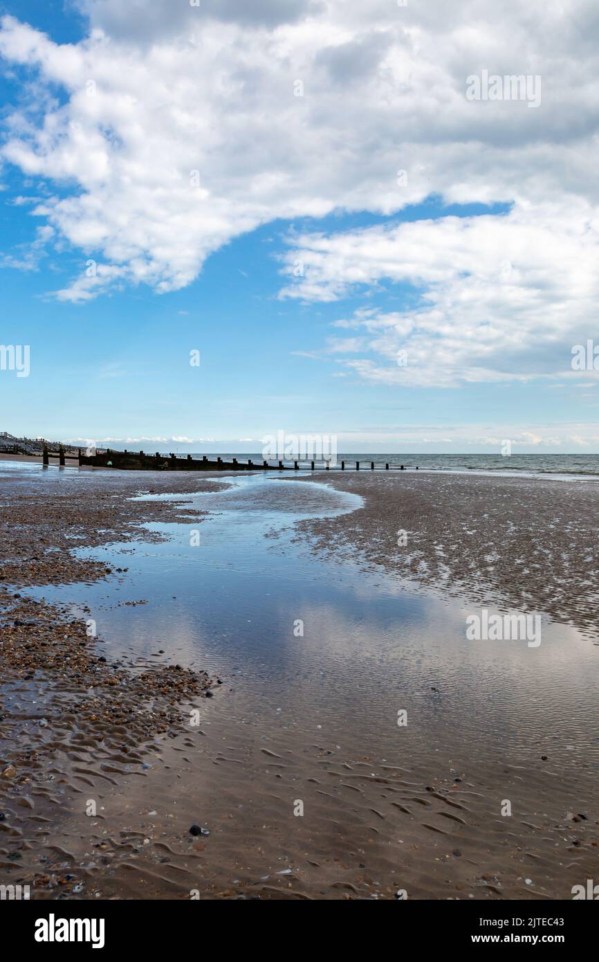 Reflexiones del cielo en el agua que se desprenden de una marea saliente, en Camber Sands en East Sussex Foto de stock