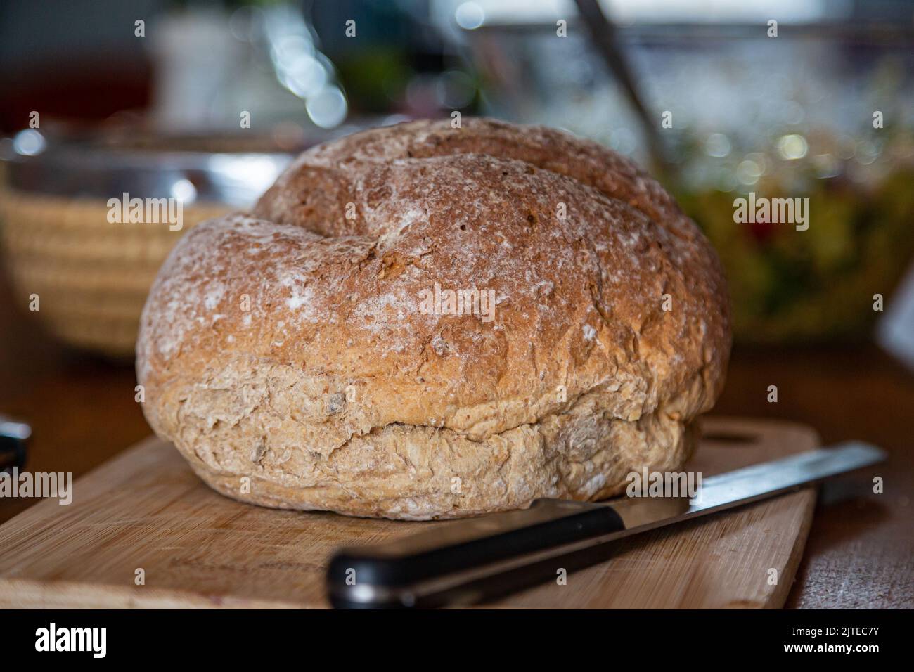 Un primer plano de una barra de pan sobre una tabla de pan, con una profundidad de campo poco profunda Foto de stock