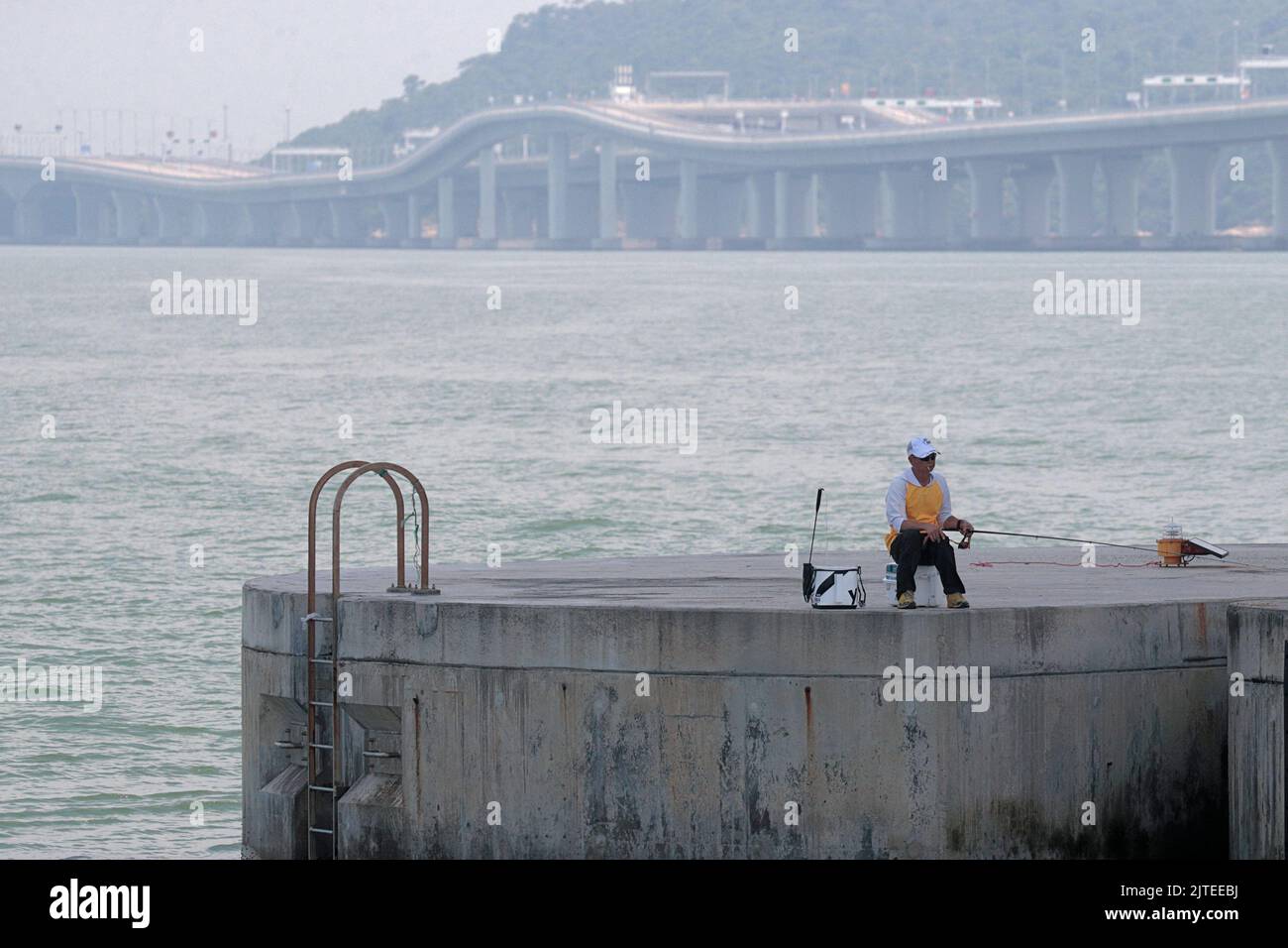 Pescador, debajo del puente de Hong Kong - Zhuhai - Macao (HZMB), sección de Hong Kong, en el delta del río Perla, Guangdong, China Foto de stock