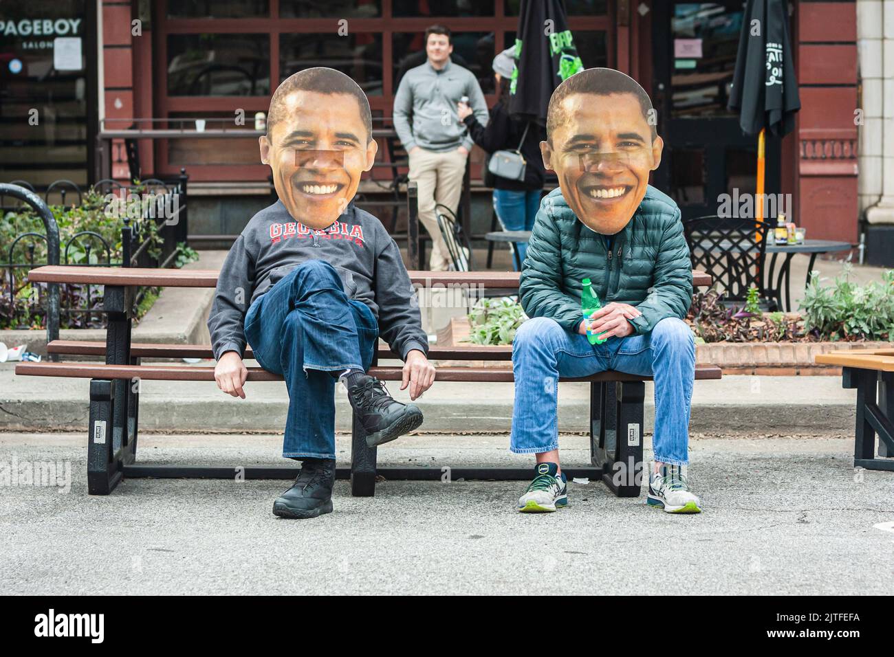 ATENAS, GA - 15 DE ENERO de 2022: Dos hombres que usan máscaras de Barack Obama sonriente y de gran tamaño se sientan en un banco de picnic el 15 de enero de 2022 en Atenas, GA. Foto de stock