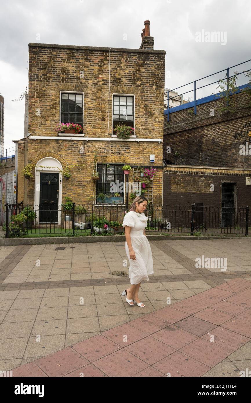 Una mujer vestida de novia caminando junto a una solitaria casa adosada a la izquierda fuera de Waterloo Station, Southbank, Londres, SE1, Inglaterra, REINO UNIDO Foto de stock
