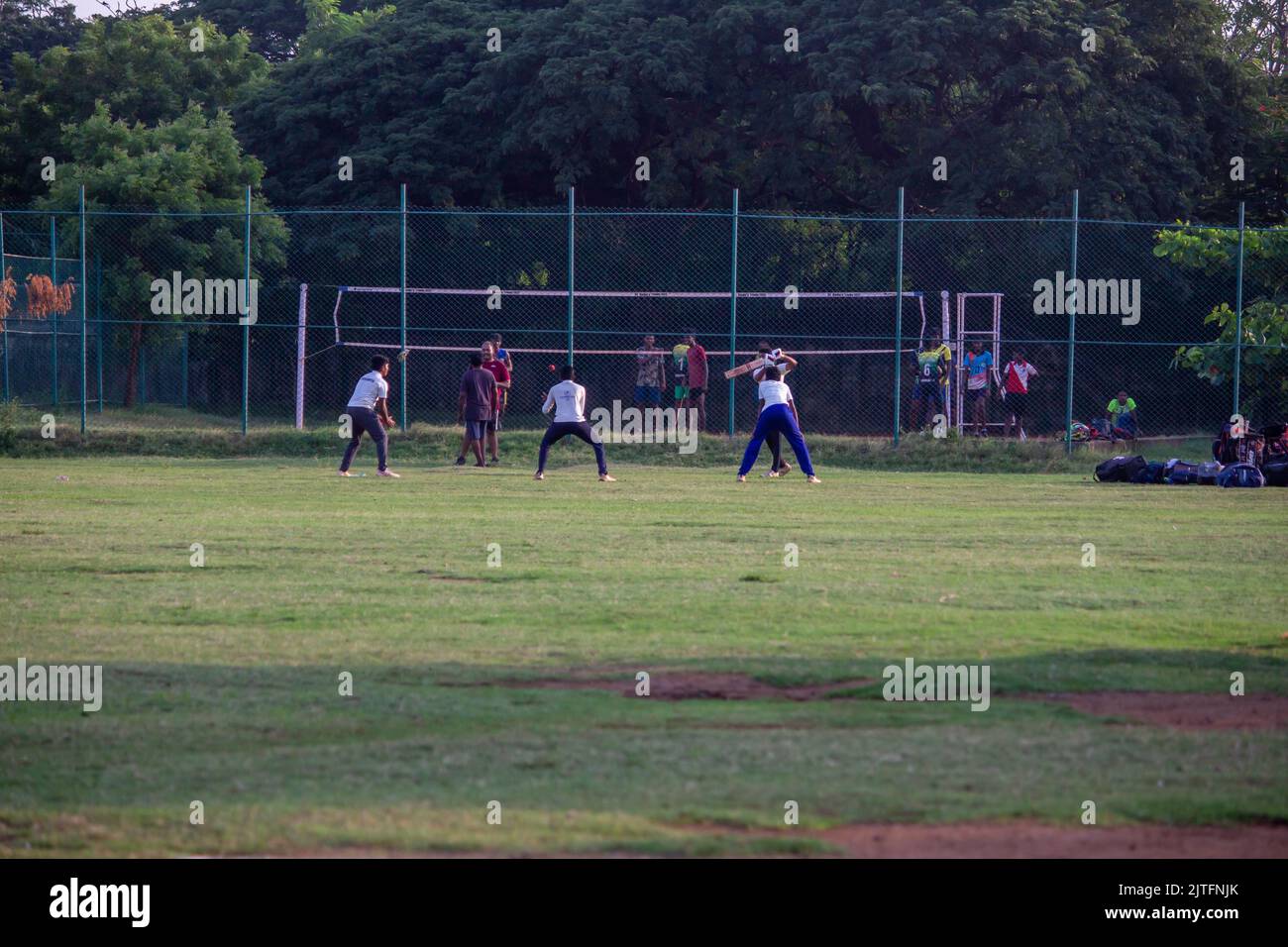 Chennai, Tamil Nadu, India - 26 de agosto de 2022: Los niños practican el juego de cricket en el patio de recreo y voleibol en la cancha Foto de stock
