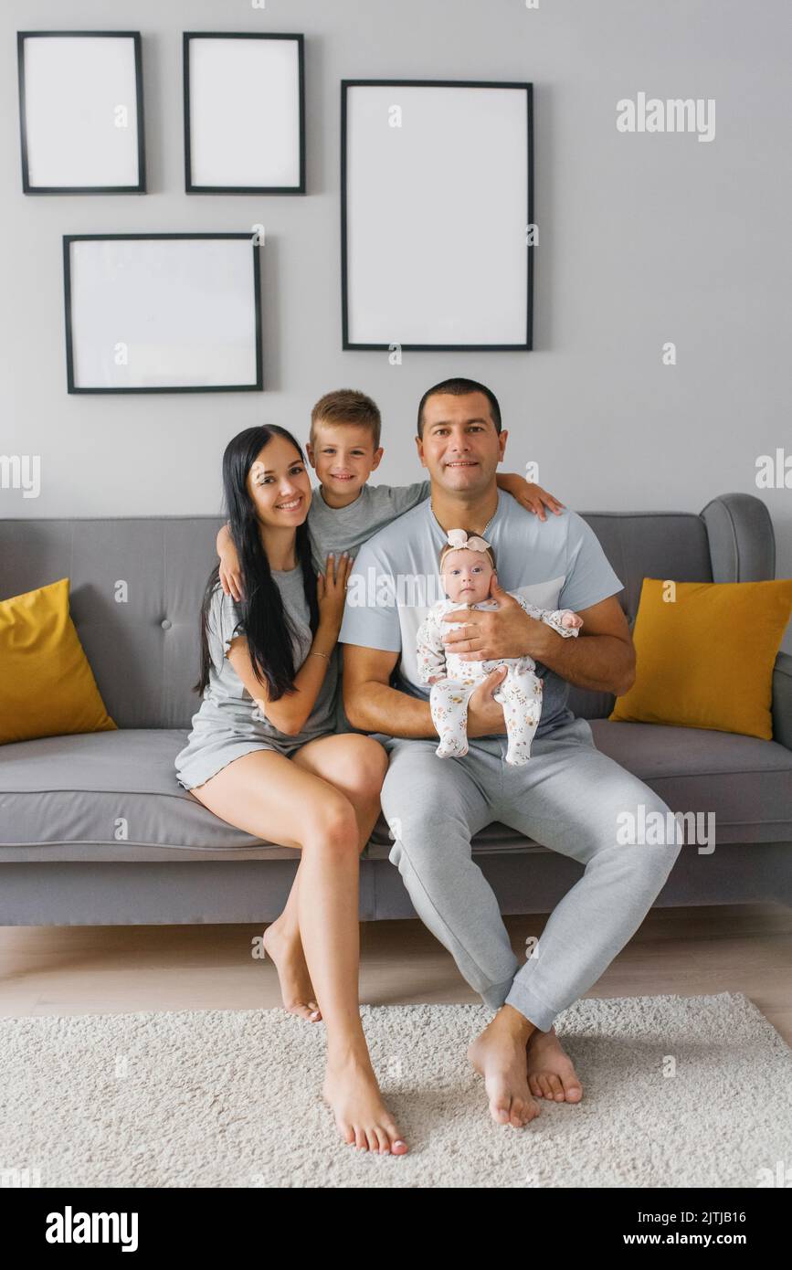 Feliz familia con dos niños están sentados en el sofá de su casa y sonriendo Foto de stock