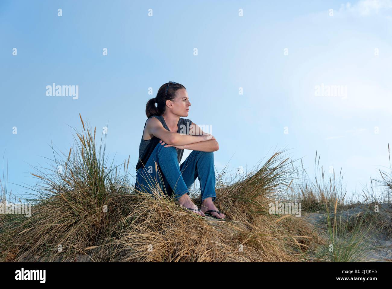mujer atractiva sentada en las dunas de arena, concepto solo. Foto de stock