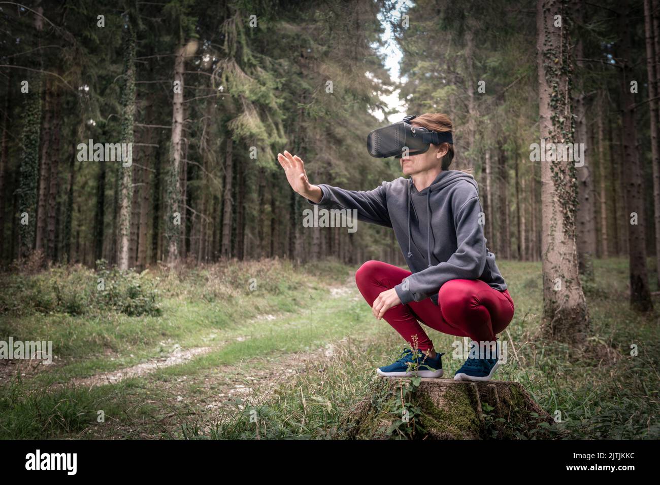 Mujer con auriculares de realidad virtual en un bosque Foto de stock