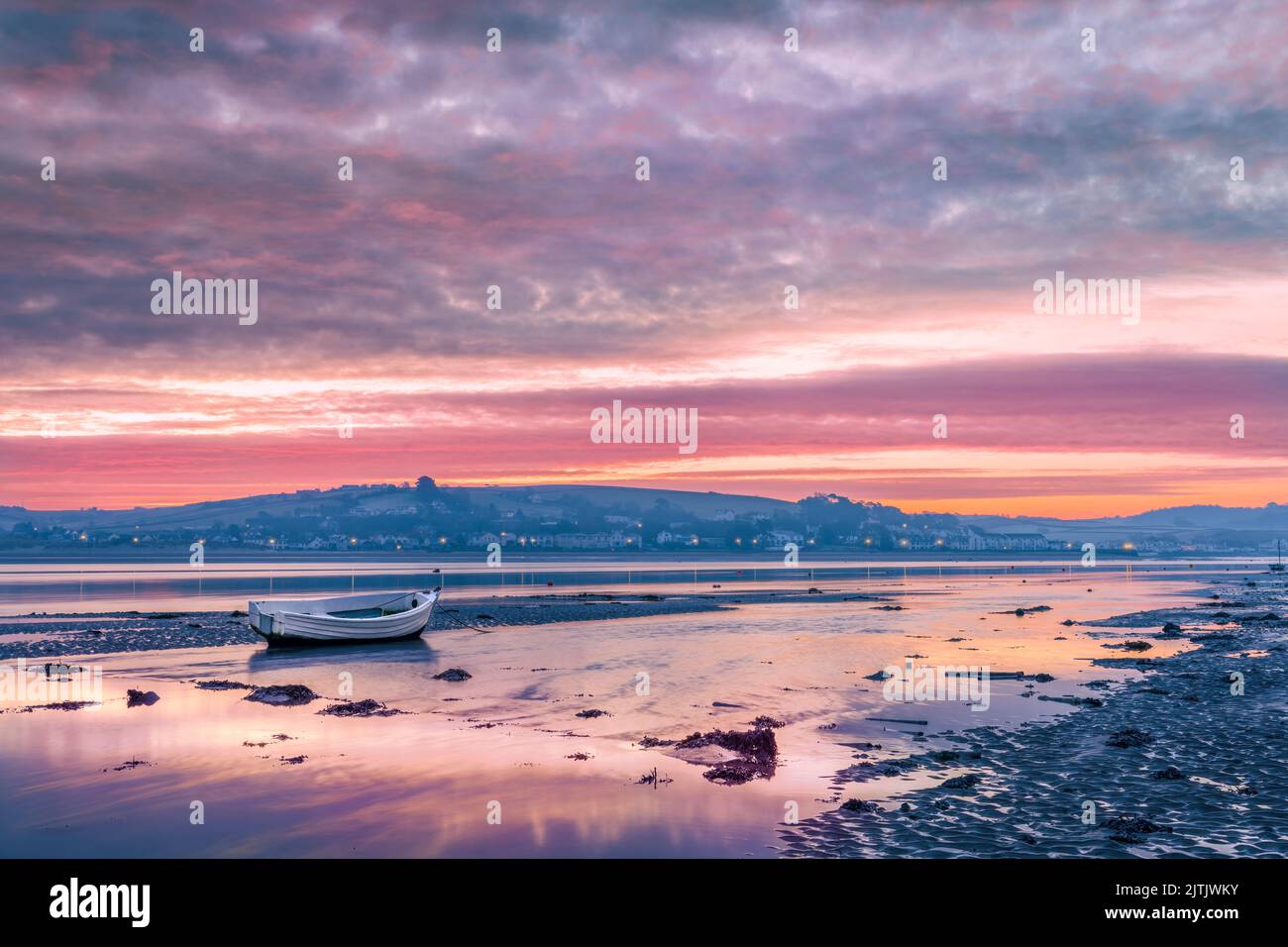 El cielo se refleja en el agua de la marea entrante mientras el amanecer rompe sobre la pequeña aldea costera de Instow en el norte de Devon, Inglaterra. Foto de stock