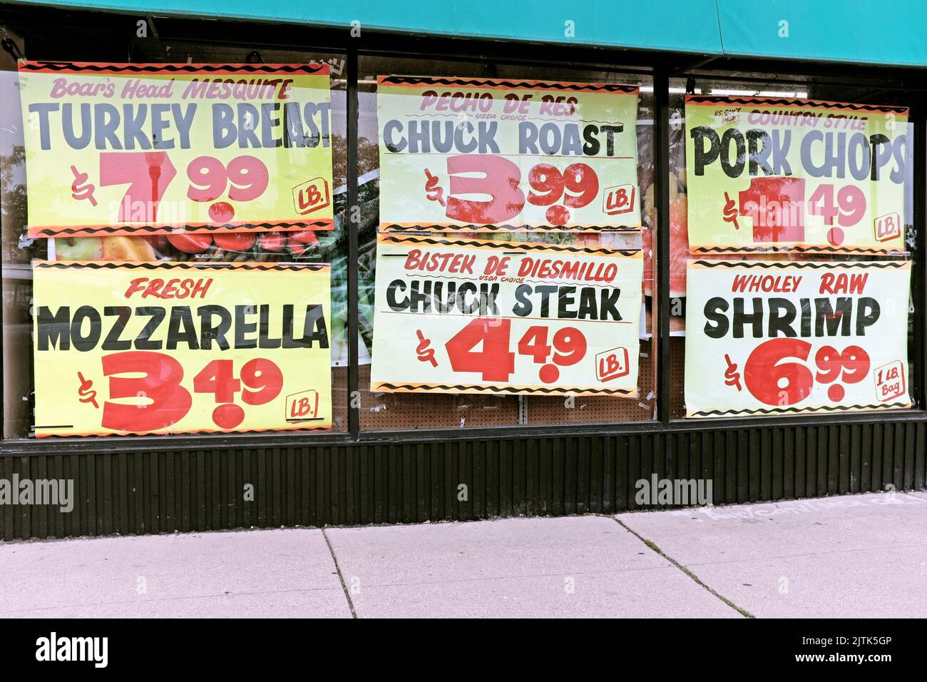 Carteles de neón exhibidos en una ventana de tienda de comestibles en Chicago, Illinois, EE.UU., muestran los precios de los alimentos en julio de 2022. Foto de stock