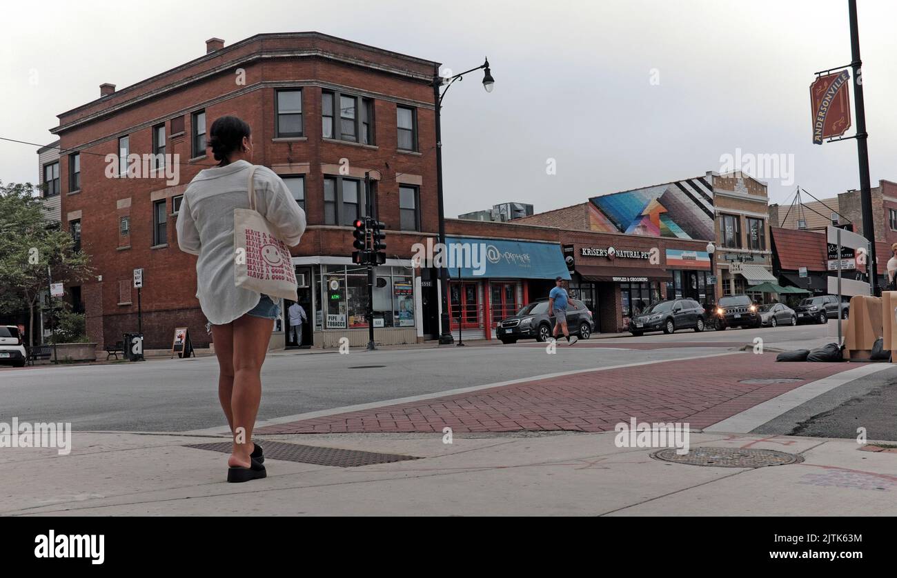 Una mujer cruza la calle durante el verano en el barrio de Andersonville en Chicago, Illinois, EE.UU. Foto de stock