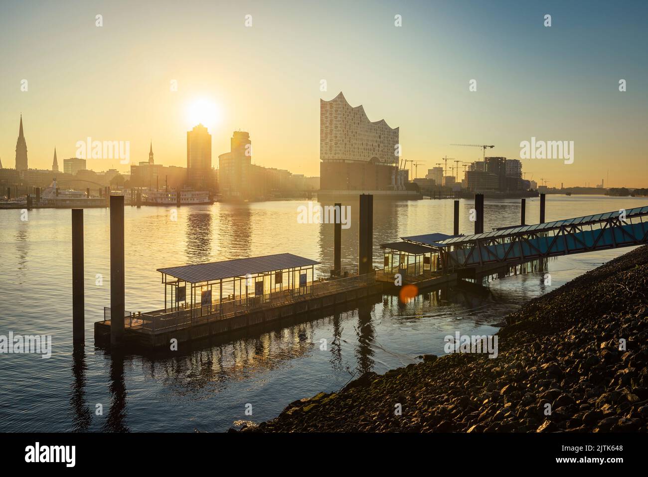 Amanecer en el Elbphilharmonie, Hafencity y un muelle de ferry en el río Elba en el puerto de Hamburgo, Alemania Foto de stock