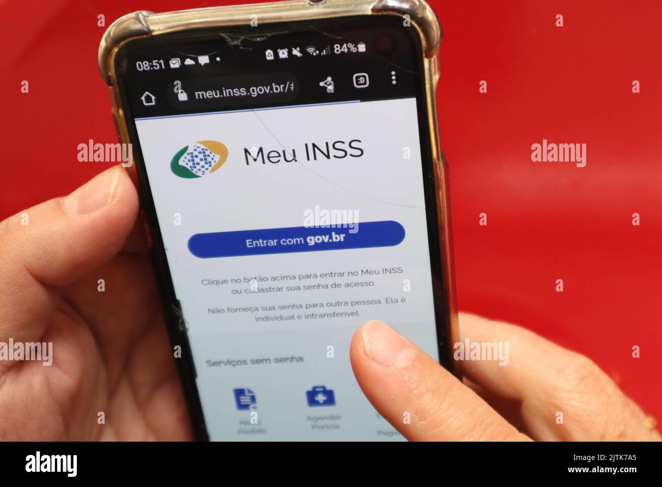 Vista superior de la pantalla táctil del smartphone que muestra el sitio Meu INSS brasileño, con fondo de color rojo. Foto de stock