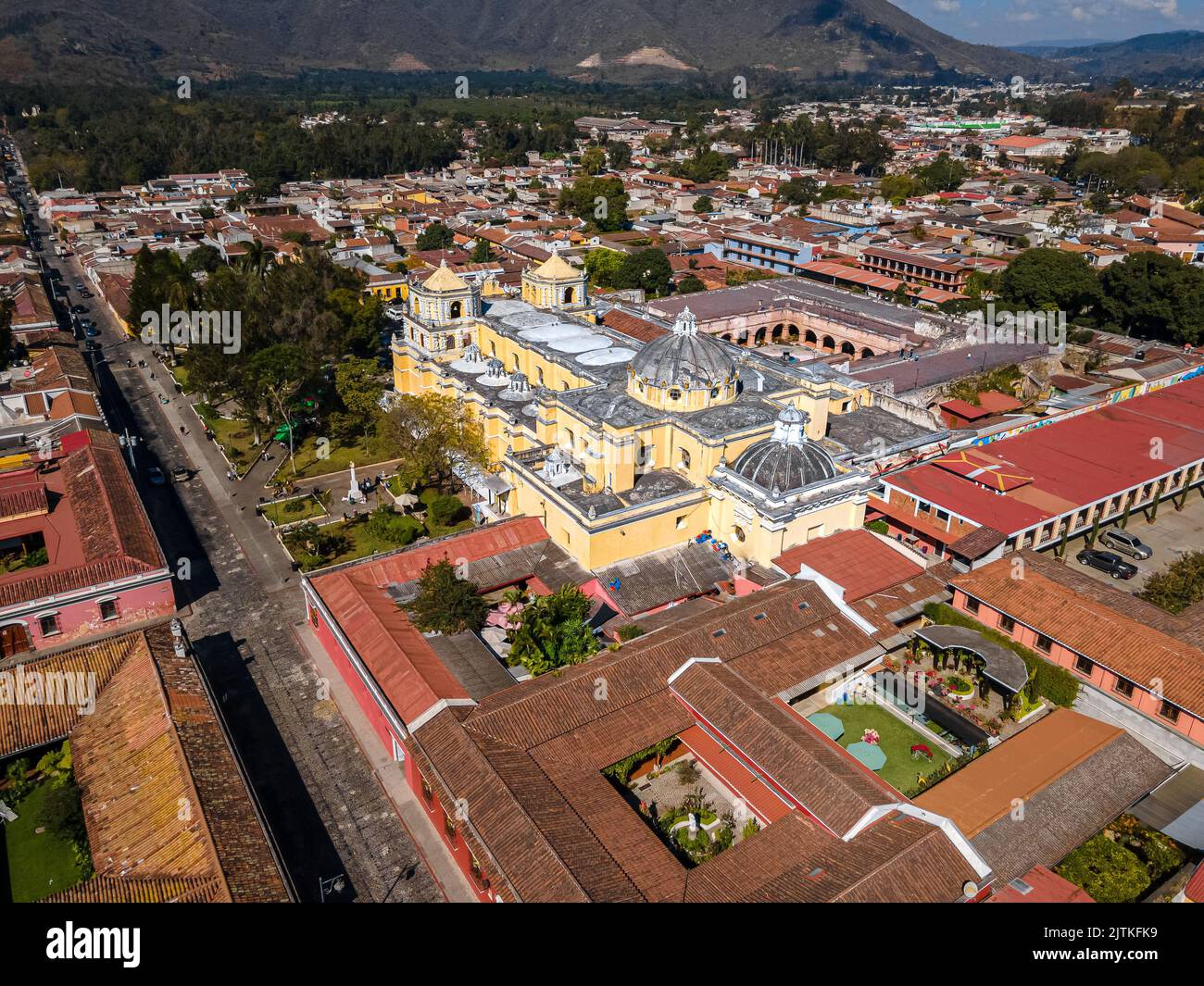 Hermoso metraje cinematográfico aéreo de la Ciudad de Antigua en Guatemala, su iglesia amarilla, el Arco de Santa Catalina y el Volcán Acatenango Foto de stock