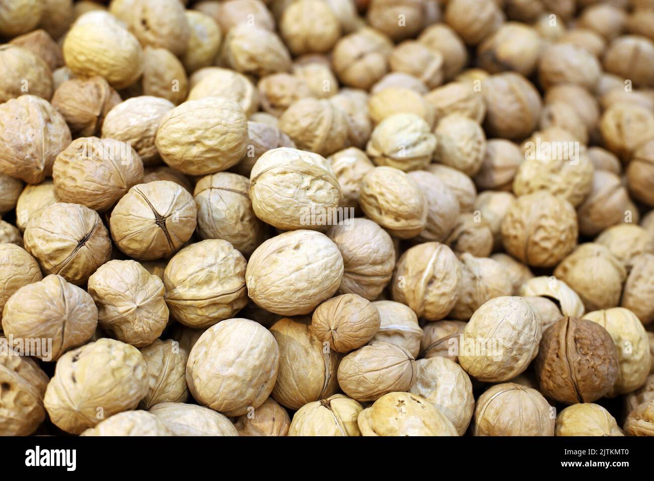 Pilas de nueces para el fondo. Frutos secos en las conchas de un mercado, alimentos proteicos para la salud cerebral Foto de stock
