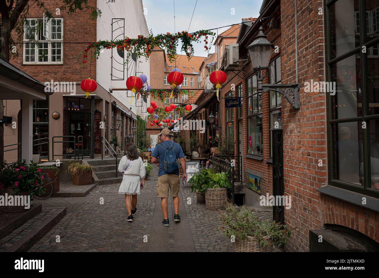 Hombre y mujer caminando en una antigua calle comercial señalizada en el centro de Odense, Dinamarca, 28 de agosto de 2022 Foto de stock
