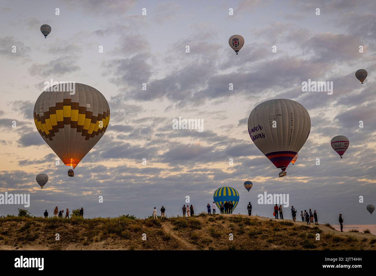 GOREME/TURQUÍA - 30 de junio de 2022: Los turistas ven el espectáculo de globos aerostáticos sobre goreme al amanecer Foto de stock