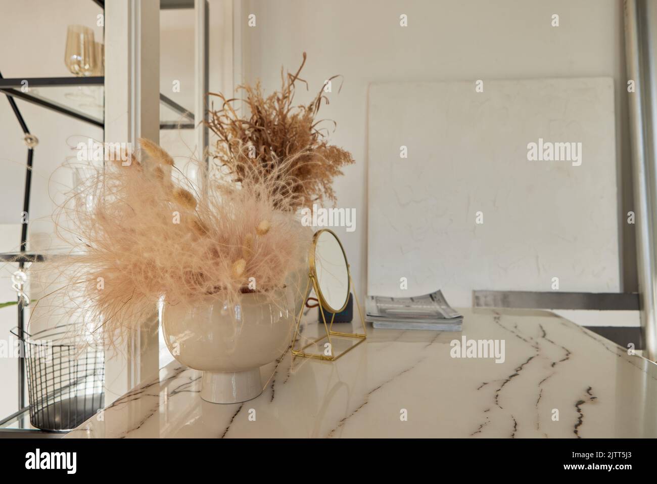 Jarrón con plantas secas y espejo cosmético sobre mesa de mármol Foto de stock