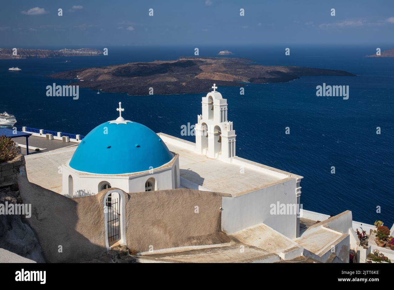 La Iglesia Católica de la Dormition - Tres campanas de Fira con su cúpula azul con vistas al mar Egeo y al volcán, Fira, isla de Santorini, Grecia Foto de stock