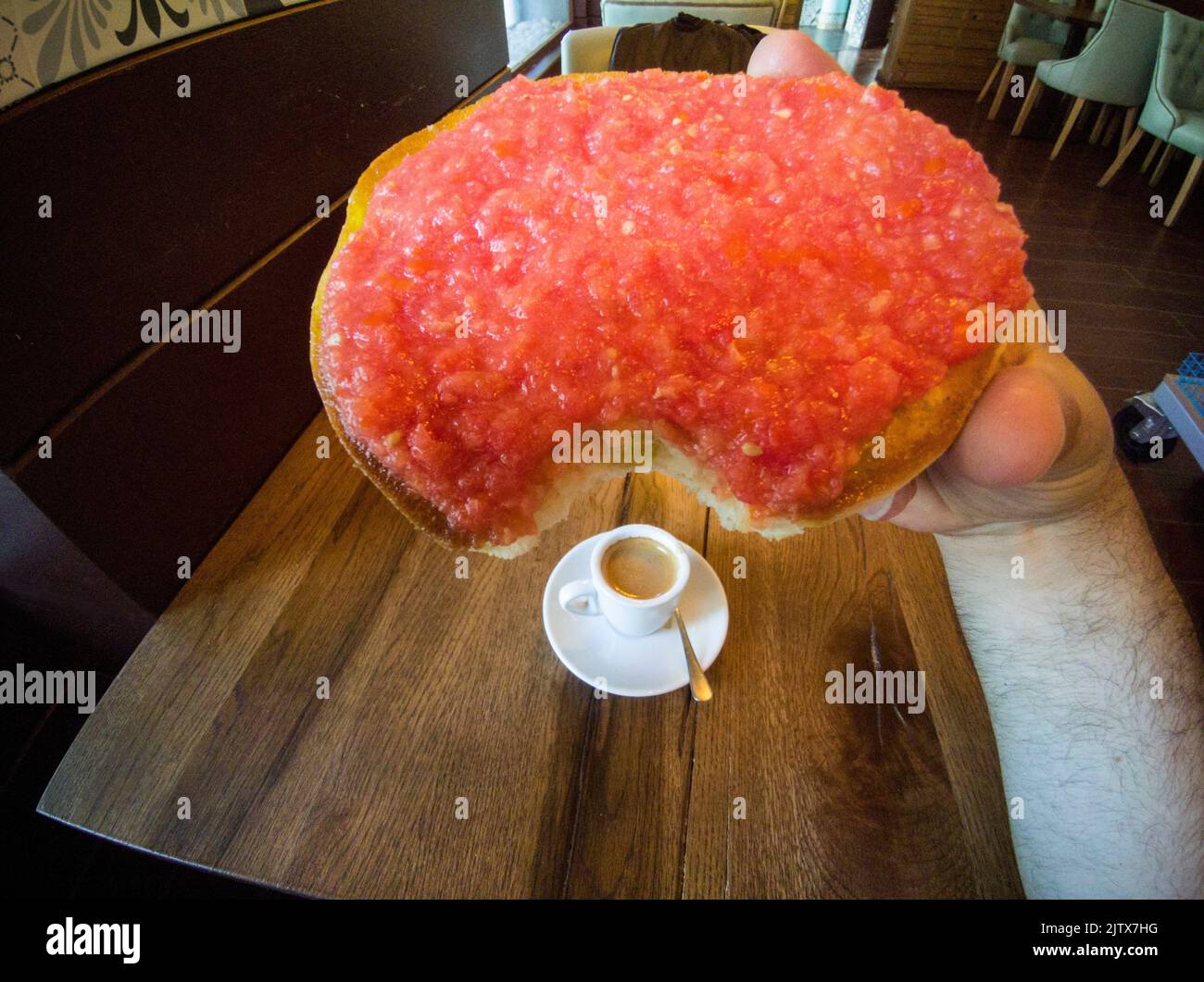 Macho comiendo tostadas de tomate natural molido. Taza de café en la mesa. Ruido suave. Foto de stock