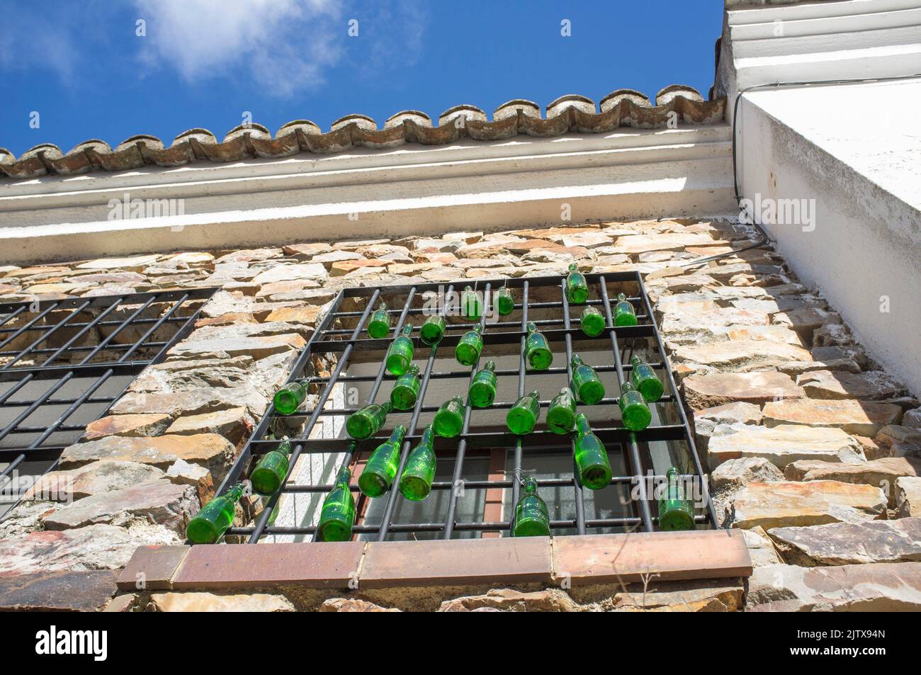 Casa de residencia rural ventana decorada con botellas de vidrio verde colgando. Vista de ángulo bajo. Foto de stock