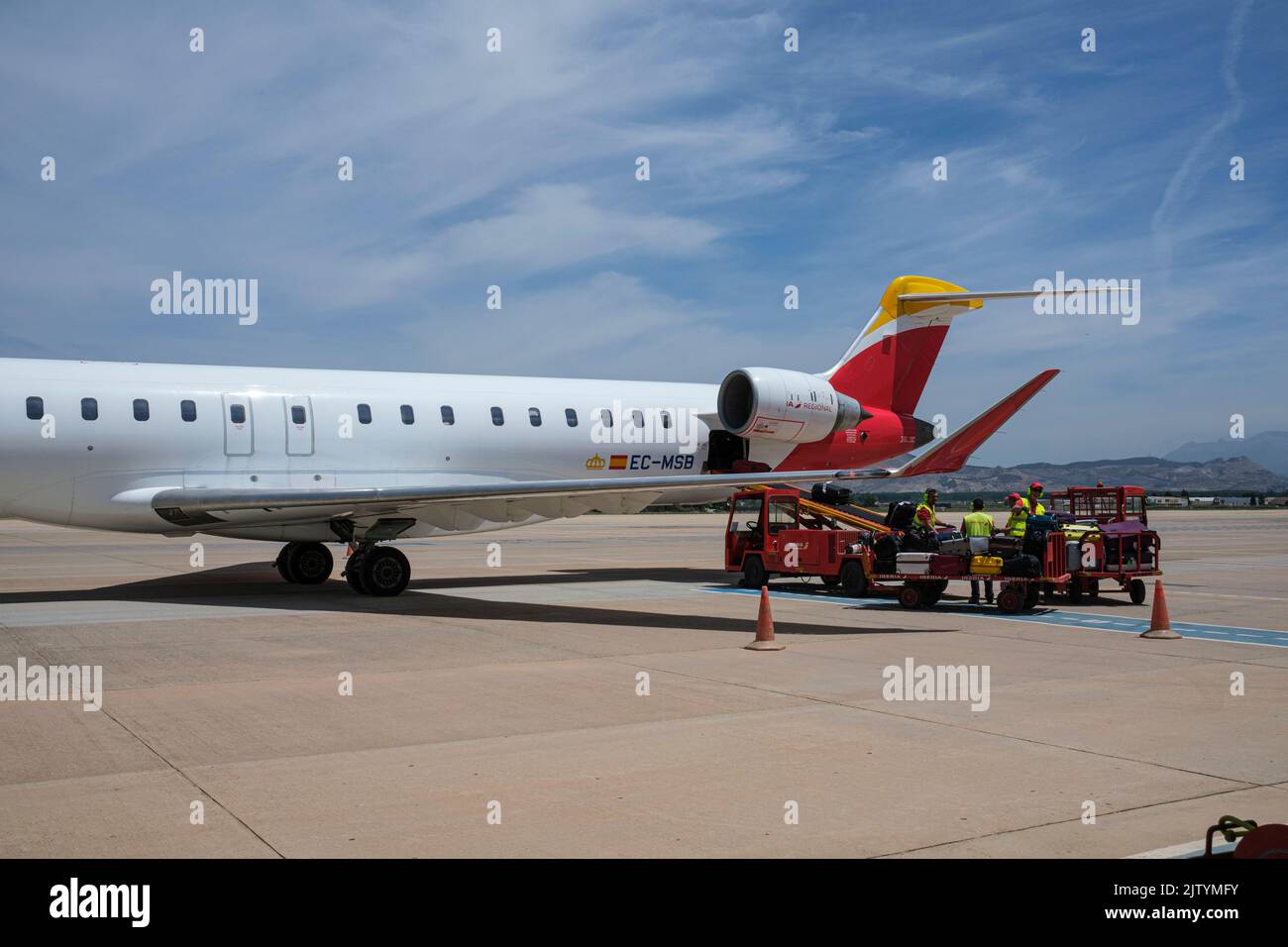 Tripulación de tierra, manipuladores de equipajes con carros cargados con maletas por un avión de Madrid a Granada, un avión Bombardier de CRJ1000, España Foto de stock