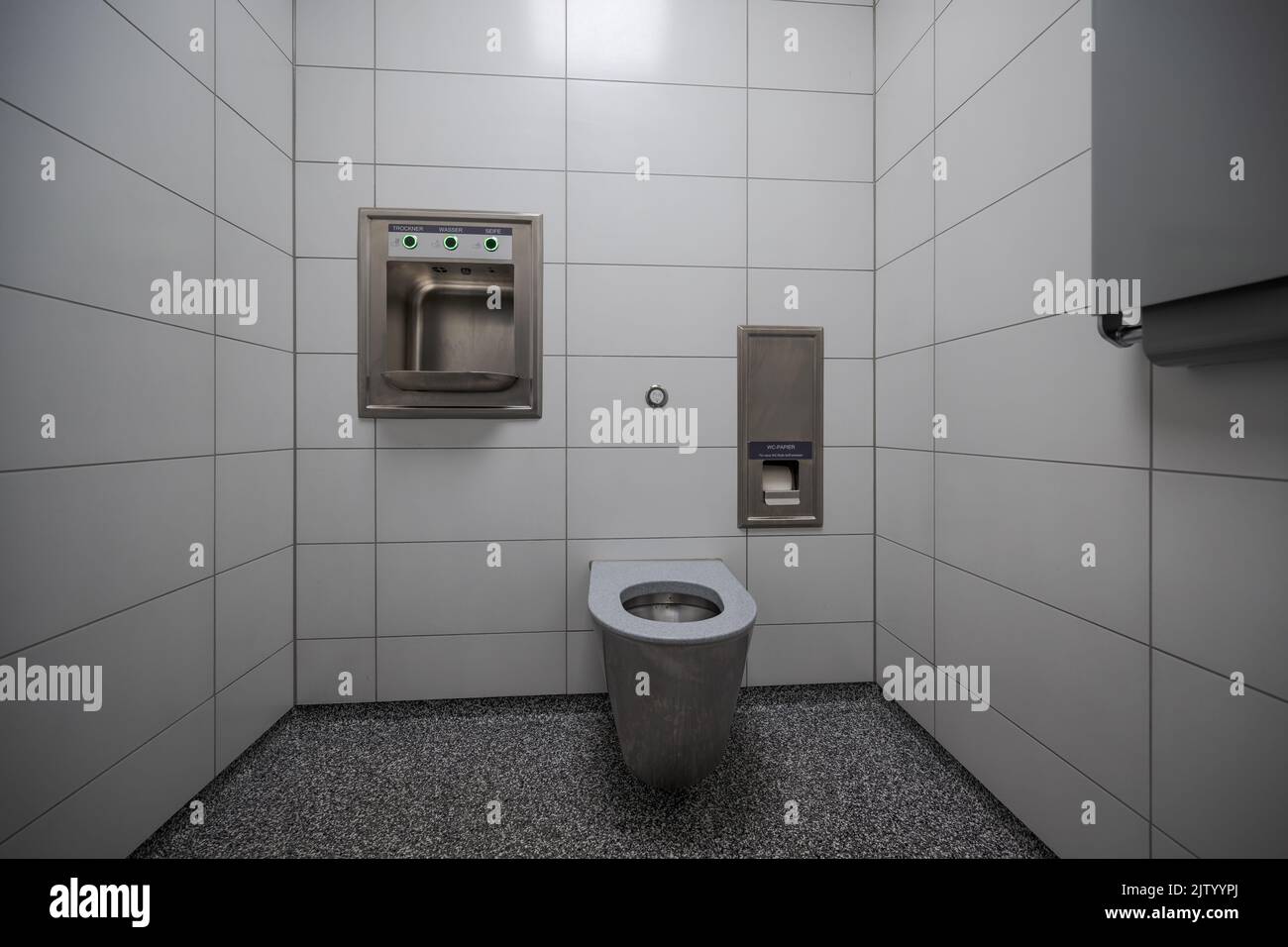 Interior de un nuevo y moderno baño público limpio con azulejos blancos y cuenco de acero inoxidable Foto de stock