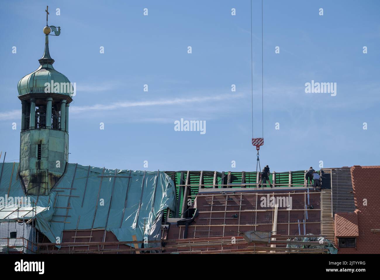 Techadores trabajando en el techo marco de la antigua iglesia con torre de cobre en el día soleado Foto de stock