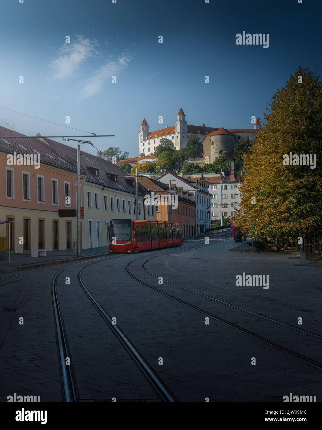 Calle con un tranvía rojo y el castillo de Bratislava al fondo - Bratislava, Eslovaquia Foto de stock