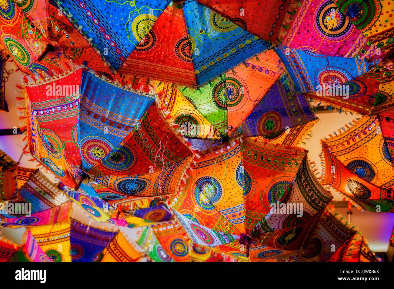 Un montón de coloridas sombrillas cuelgan de un techo iluminado, Foto de stock