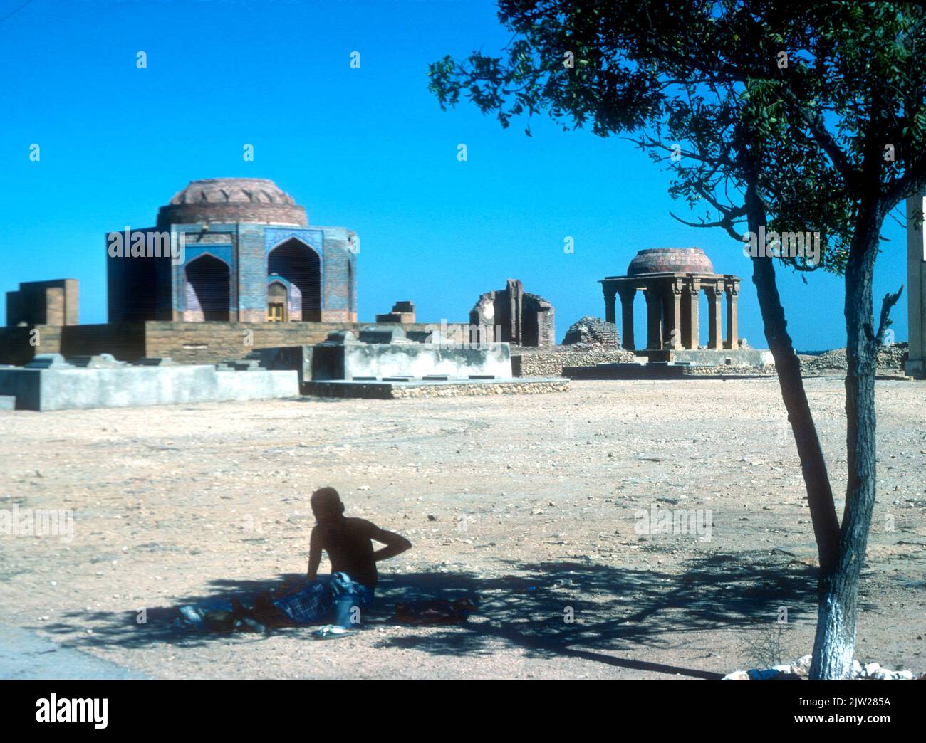 Mendigo esperando a la sombra en la necrópolis de Thatta en Sindh Pakistán Foto de stock