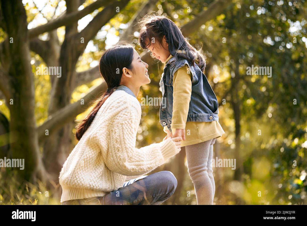 joven madre asiática e hija preescolar disfrutando de la naturaleza pasando un buen rato al aire libre en el parque Foto de stock