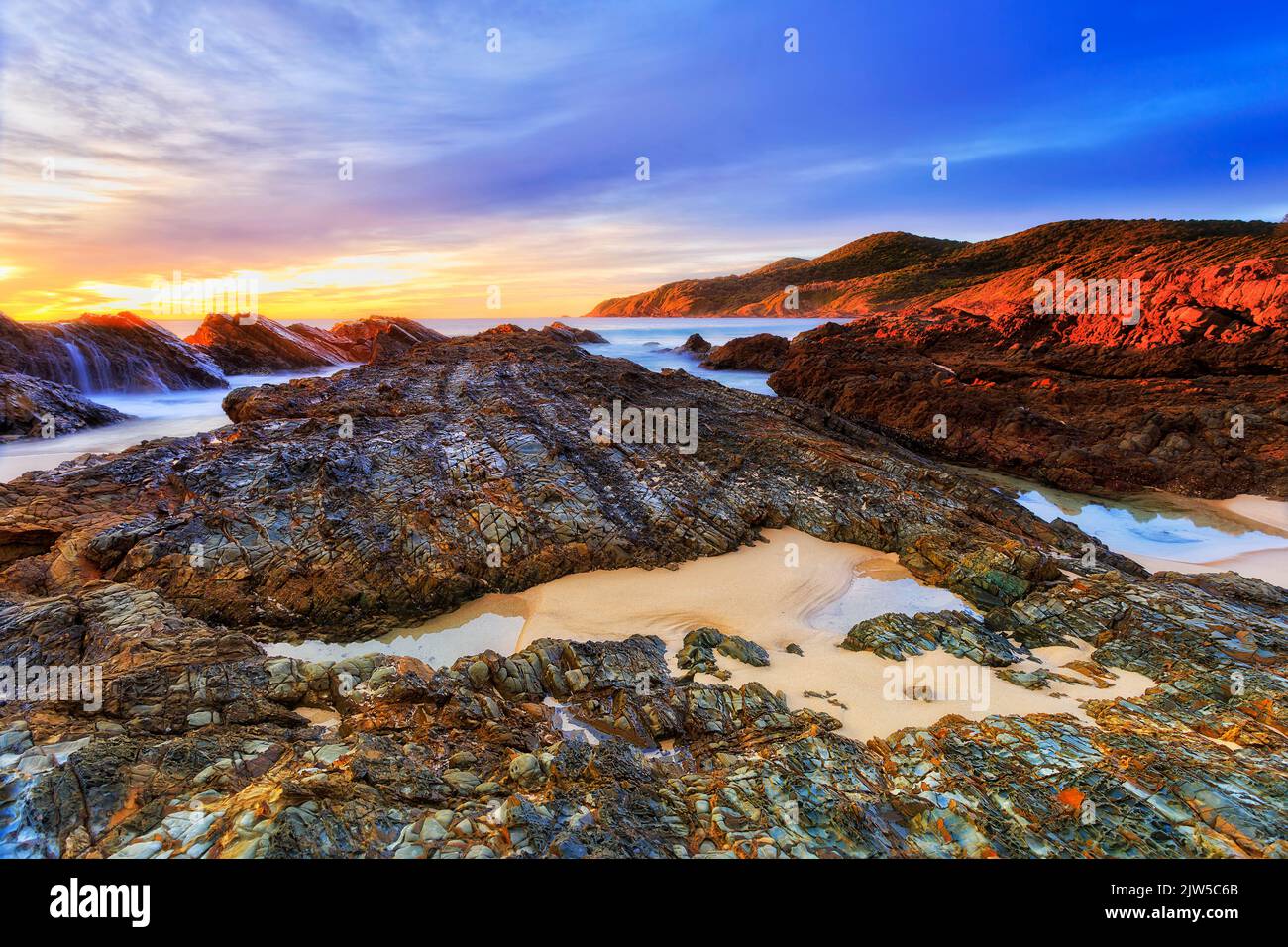 Salida del sol escénica y colorida del paisaje marino en las rocas de la playa Burgess en la ciudad de Forster, en la costa del Pacífico australiano. Foto de stock