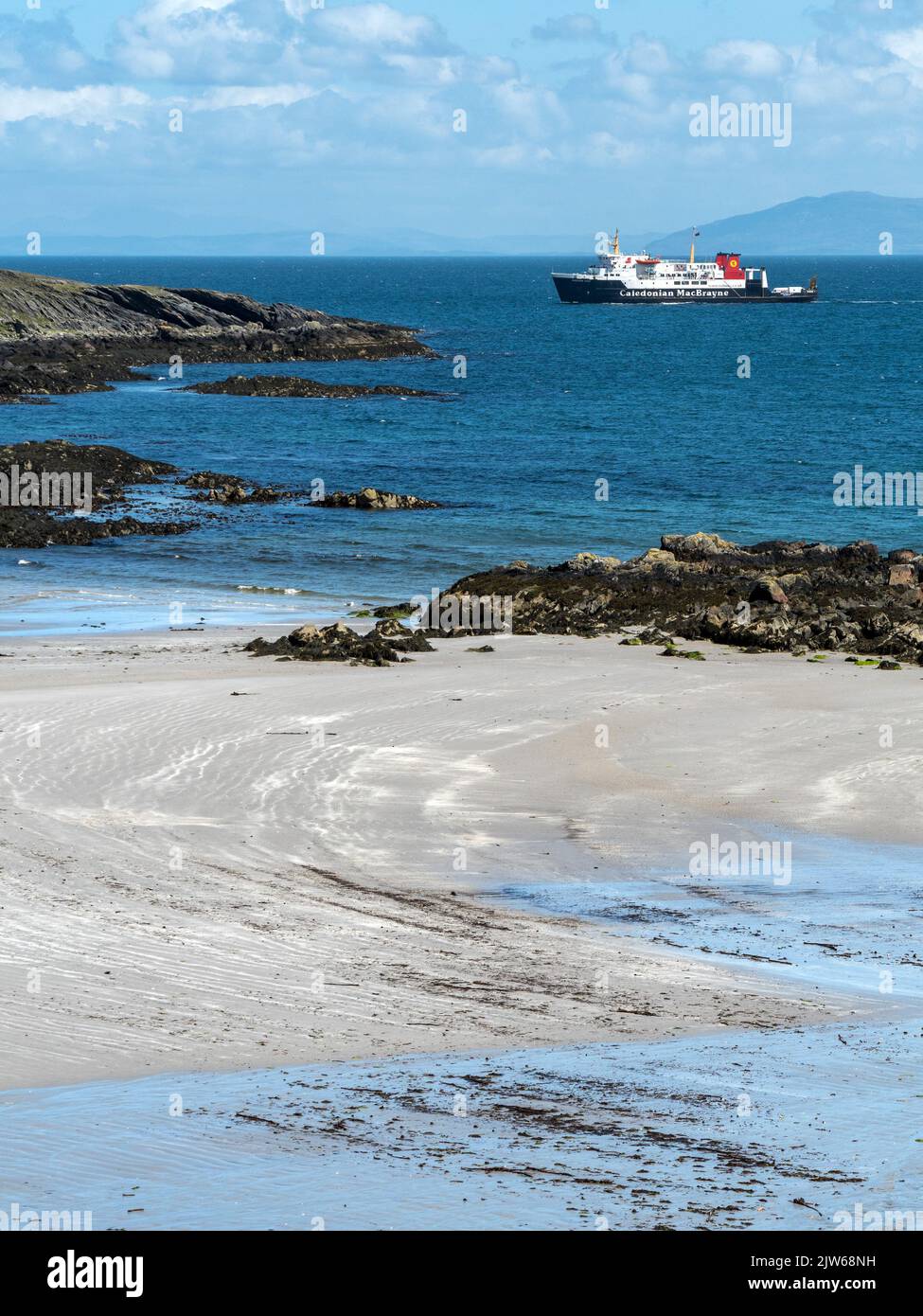 El ferry de MacBrayne Caledonian se acerca a la isla de Colonsay en ruta desde Islay, con la playa de arena de Queen's Bay en primer plano. Foto de stock