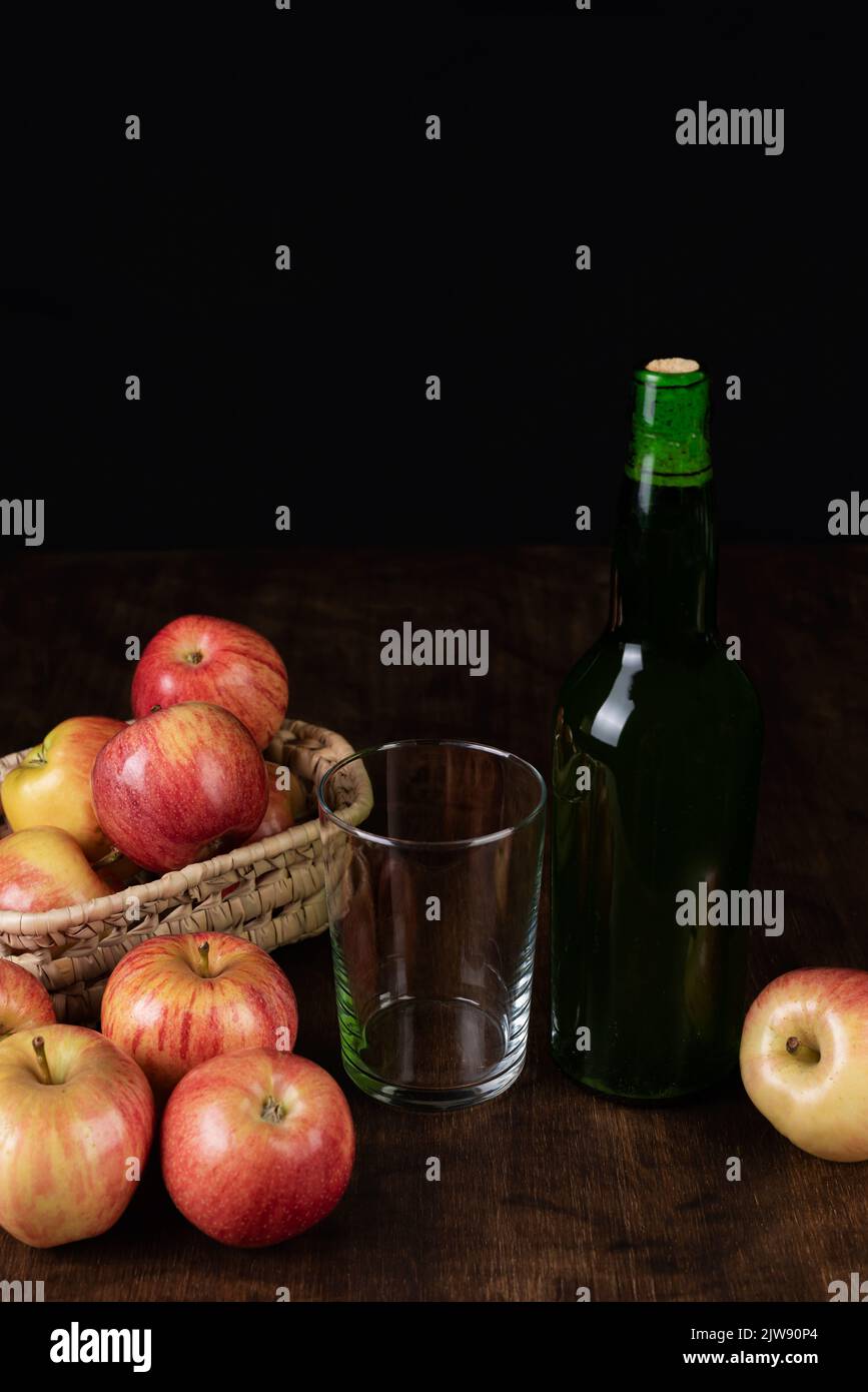 Botella de sidra junto a un vaso vacío y algunas manzanas. Foto de stock