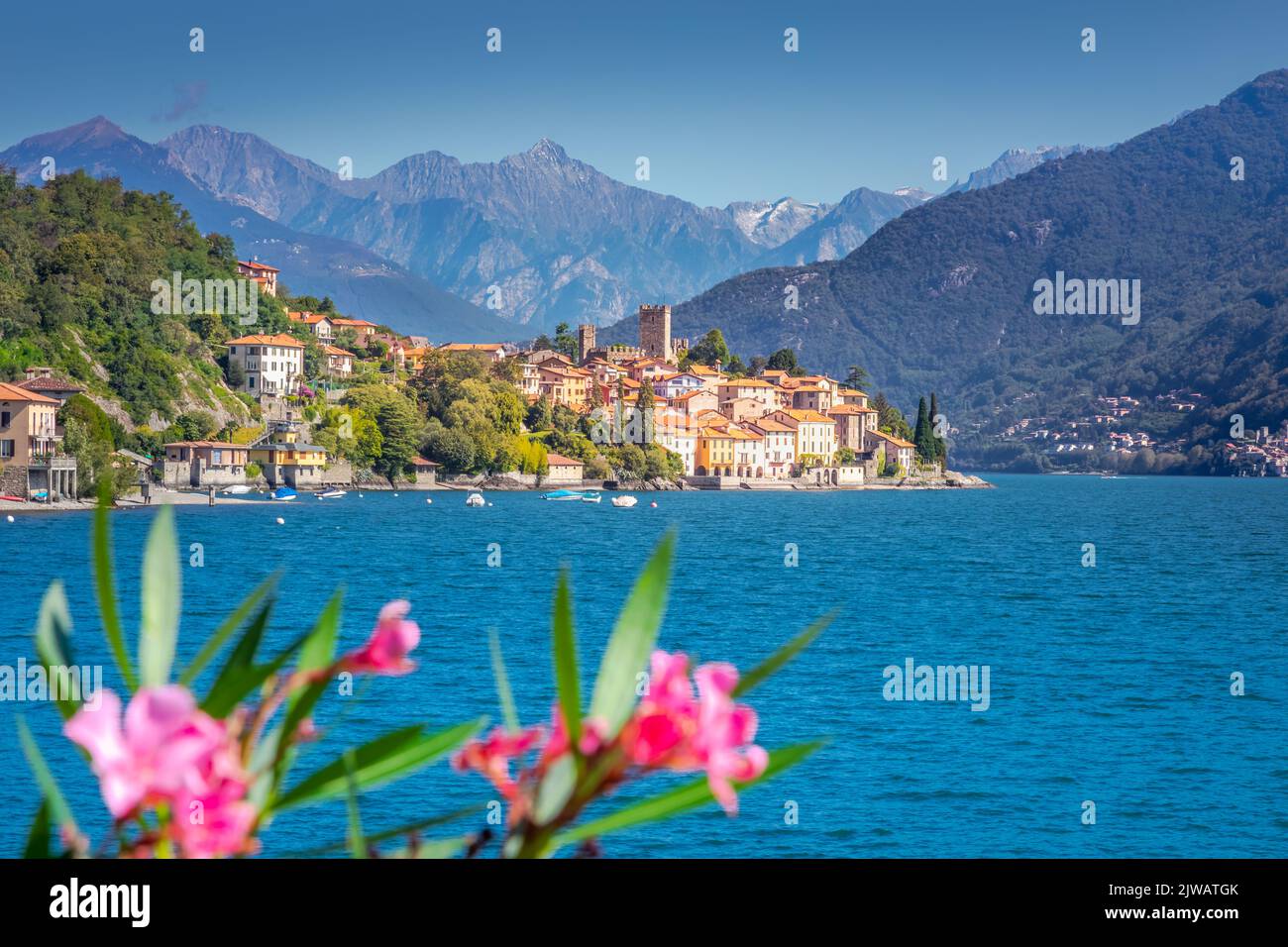 Idílica costa del Lago Como con pueblo y lancha motora en un día soleado, Italia Foto de stock
